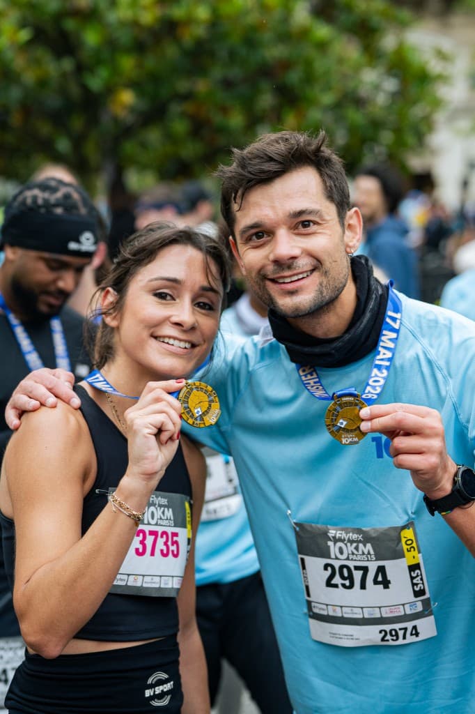 Deux coureurs et coureuses montrant leurs médailles après la course